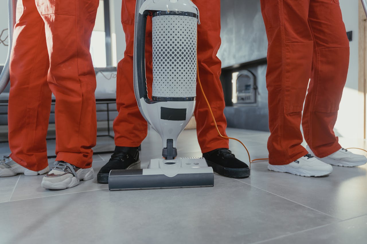 services-02 Team of professional cleaners in red uniforms using a vacuum cleaner indoors.